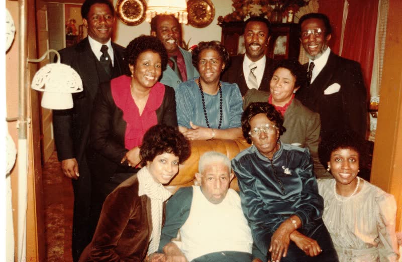 Hiram and Gertrude Hill seated in the center of a living room, surrounded by their children